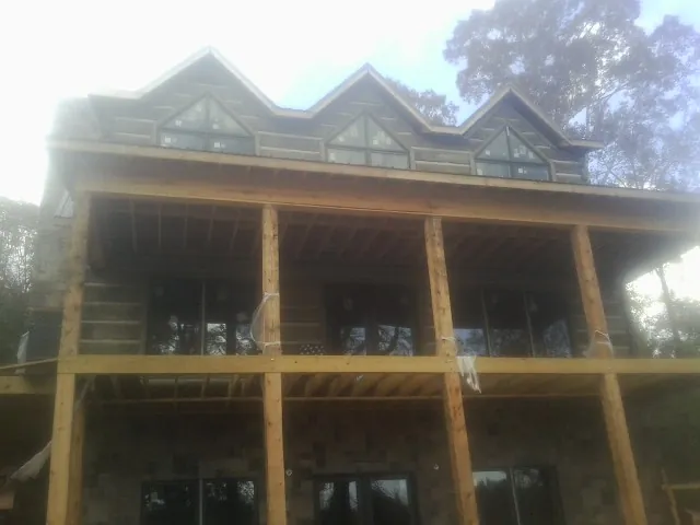 Dormers and porch framing on a large log home under construction — Roof Coating work by our crew in Haywood