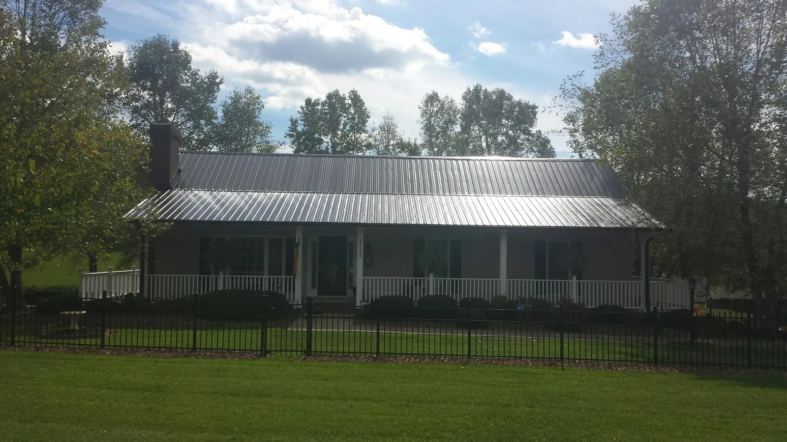 Gray metal roof on a brick ranch with a full width front porch — Gutter Guard Installation work by our crew in Haywood