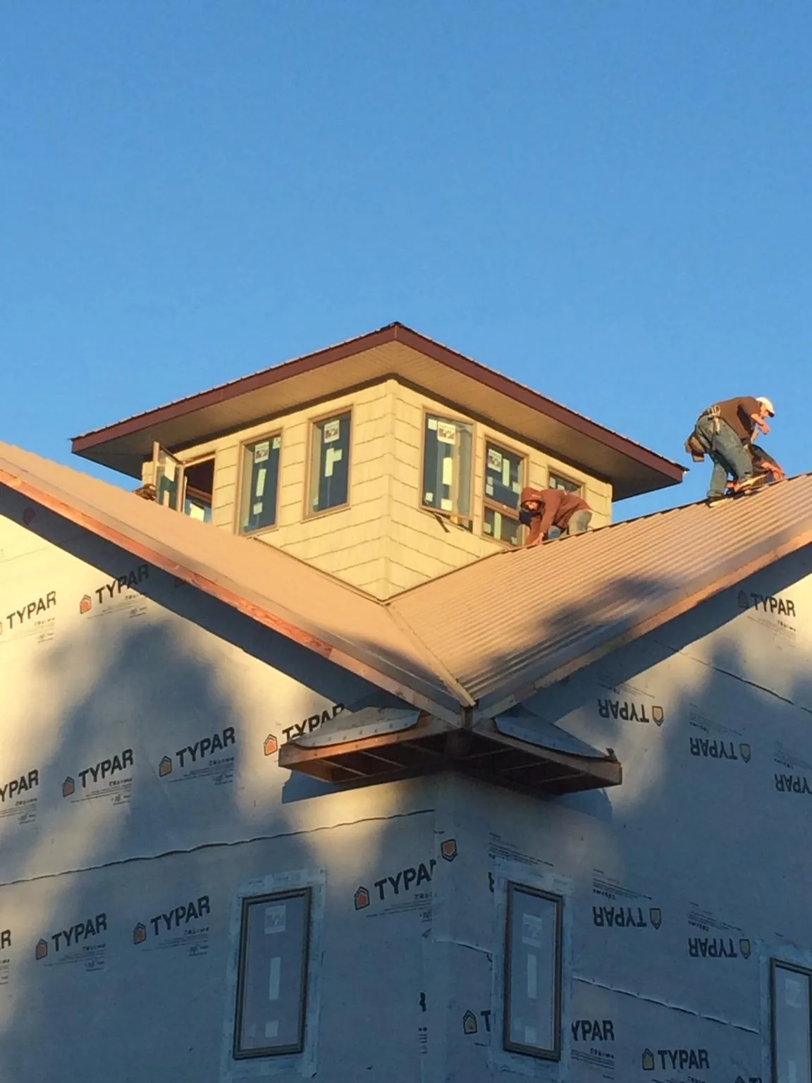 Roofers working around a rooftop cupola on a new metal roof at sunset — Roof Waterproofing in Haywood by Roofing Brothers